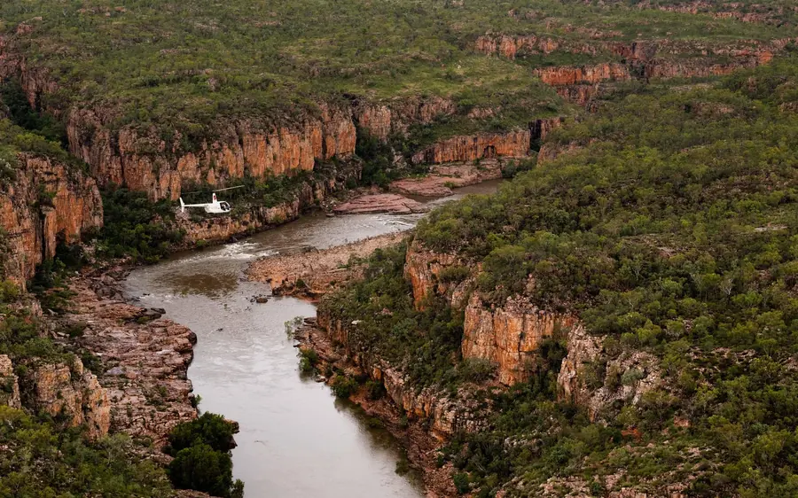 The gorge from the air with a tiny white helicopter over the river bend